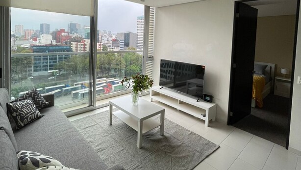 A modern living room with a large TV, a sofa, and a coffee table. - Polanco beautiful 1 bedroom Apartment, next to shopping mall. Great views, WiFi (Ciudad de México)