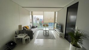 A modern living room with a sofa, coffee table, and a TV. There is a large window with a view of buildings. - Polanco beautiful 1 bedroom Apartment, next to shopping mall. Great views, WiFi (Ciudad de México)