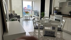 A modern kitchen with white cabinets, a stove, and a microwave. There is a dining area with a white table and chairs. - Polanco beautiful 1 bedroom Apartment, next to shopping mall. Great views, WiFi (Ciudad de México)