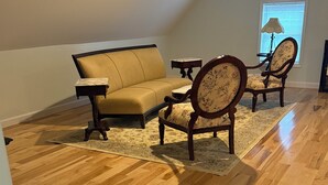 A room with a wooden floor, a sofa, two chairs, a small table, and a lamp. - Charming 2-bedroom barndominium in historic Appomattox Virginia. (Appomattox)