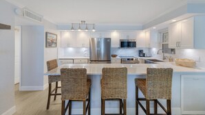A modern kitchen with a central island, stainless steel appliances, and light blue cabinetry. - BG Beach Club 3C | 3BR/2BA Boca Grande | Pool View (Boca Grande)