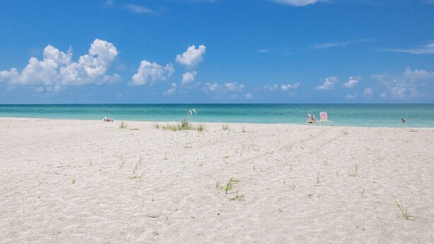 A wide sandy beach with clear turquoise water and a few people in the distance. - BG Beach Club 3C | 3BR/2BA Boca Grande | Pool View (Boca Grande)