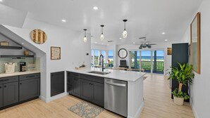 Una cocina moderna con una isla central, muebles oscuros y vistas a un balcón.
