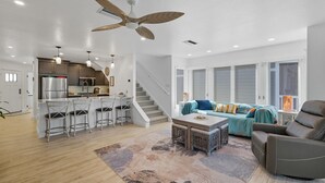 Amplia sala de estar con cocina, comedor con taburetes de bar, un conjunto de sofás y una chimenea.