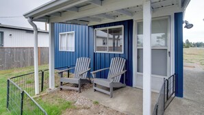 Varanda coberta com duas cadeiras Adirondack, uma porta e uma janela.