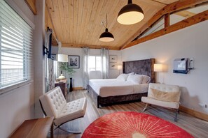A bedroom with a bed, a chair, a desk, and a red rug. - Walkable Beach Bungalow in Ocean Shores! (Ocean Shores)