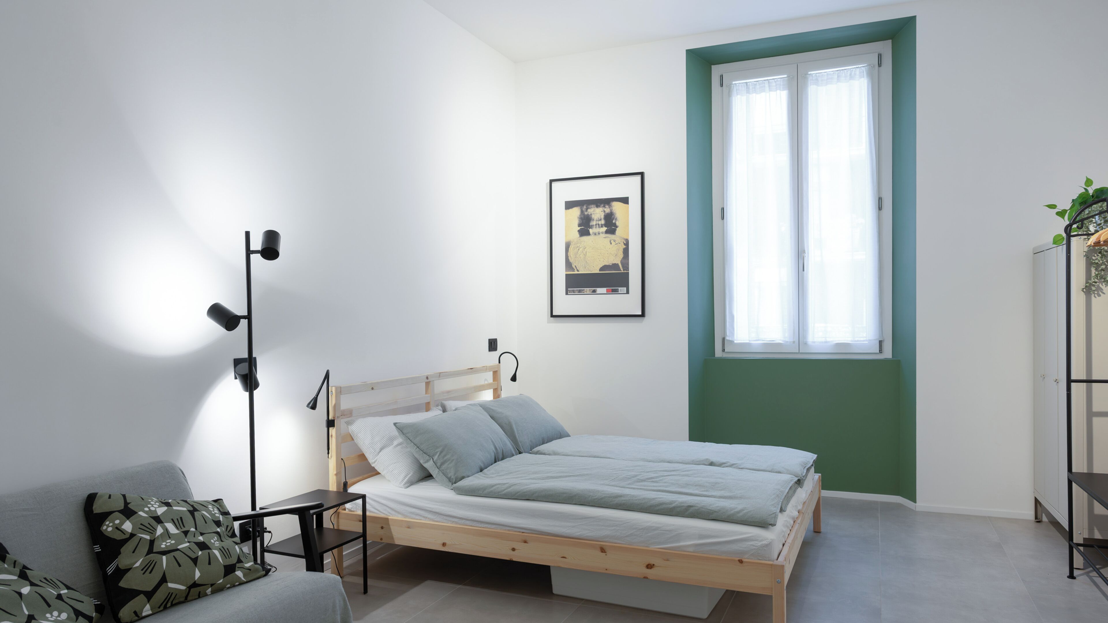 A bedroom with a bed, bedside table, lamp, and a framed picture on the wall.