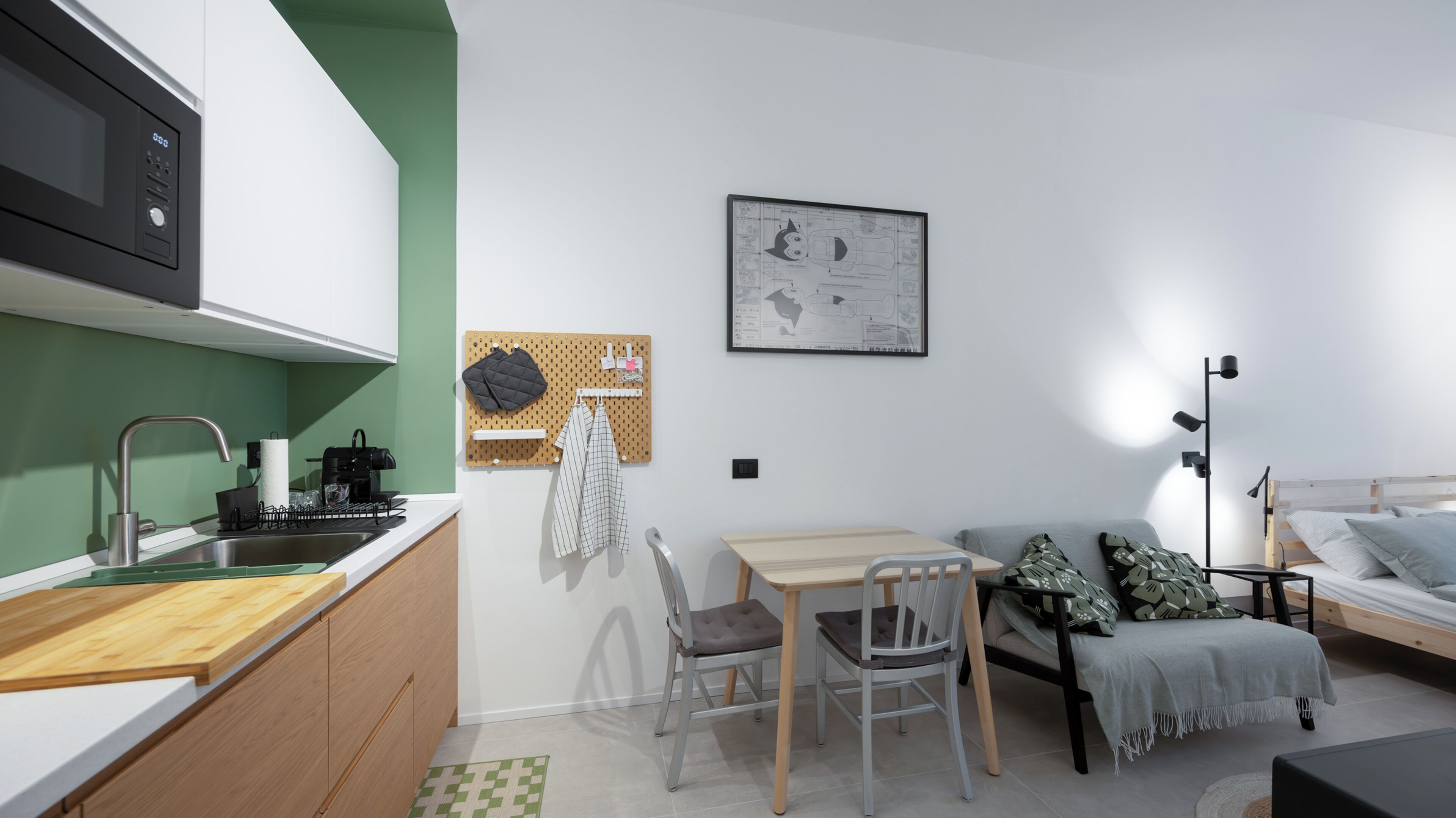 Ein kompakter Wohnraum mit Küchenzeile, Essbereich und Bett.