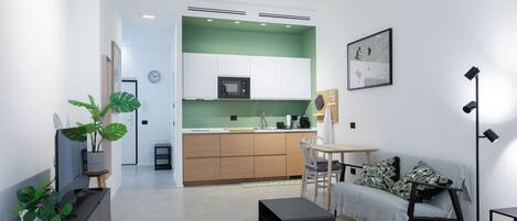 Un salon moderne avec un canapé, une table basse et un meuble pour la télévision, agrémenté d’une plante.