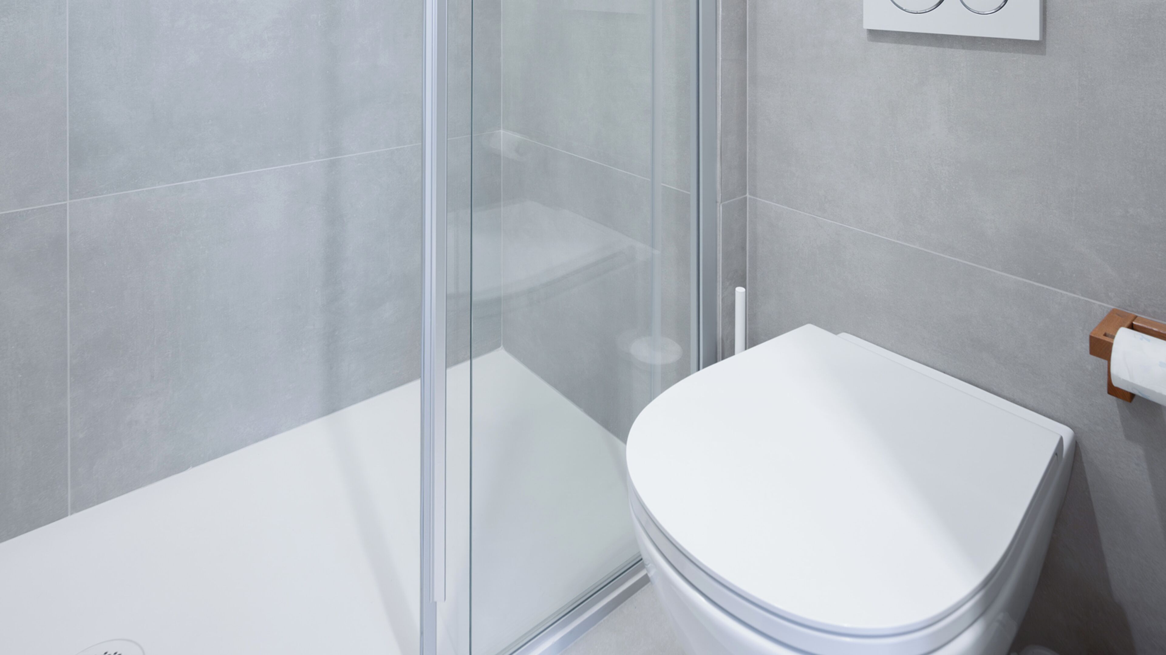 A modern bathroom with a glass shower enclosure, a white toilet, and a towel rack.