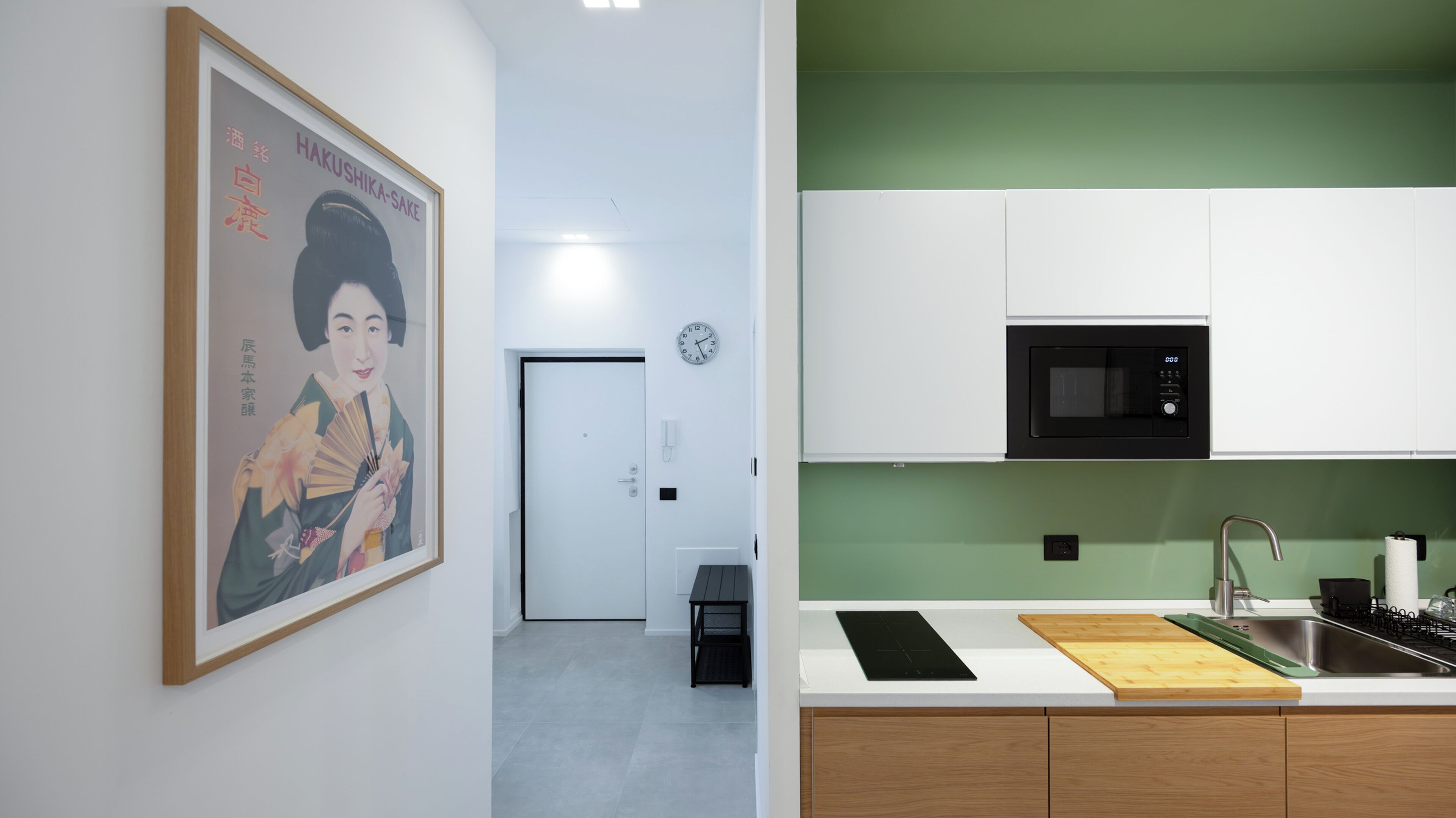 Une cuisine moderne avec des armoires blanches, un micro-ondes noir et un pare-feu vert.