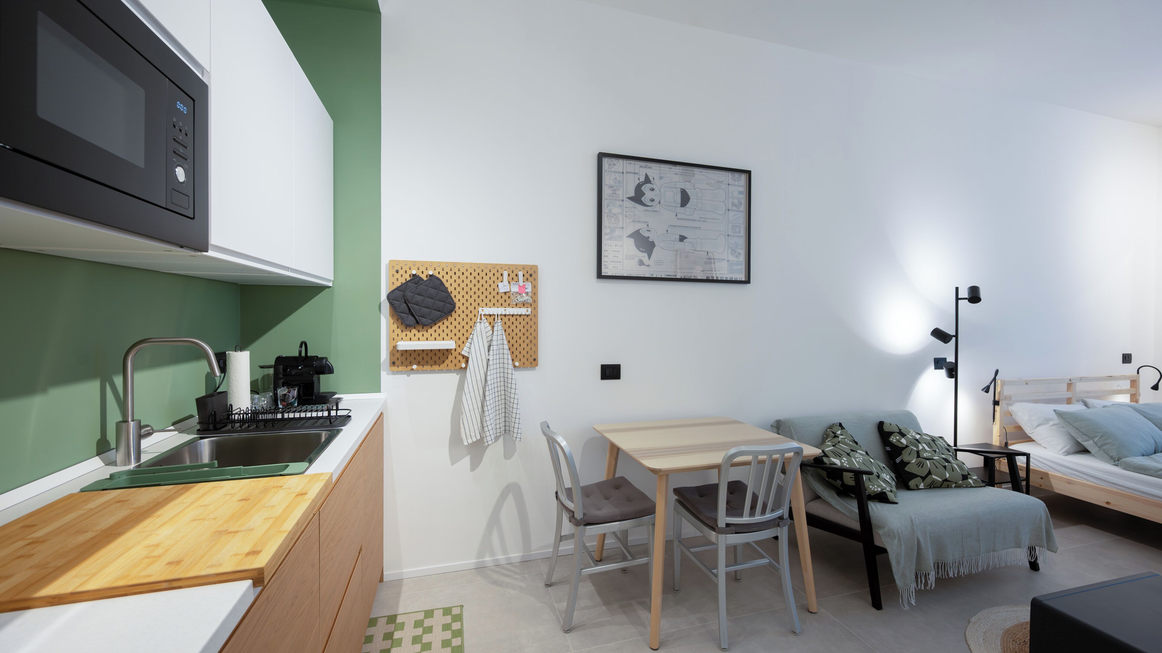 A compact studio apartment with a kitchenette, a dining area, a bed, and a seating area.