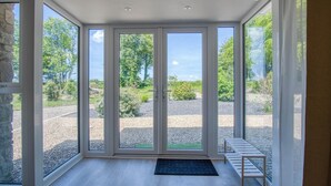 A room with large glass doors leading to a gravel area with trees and a clear sky. - The Pig Sty - 1 Bedroom Studio - Princes Gate (Narberth)