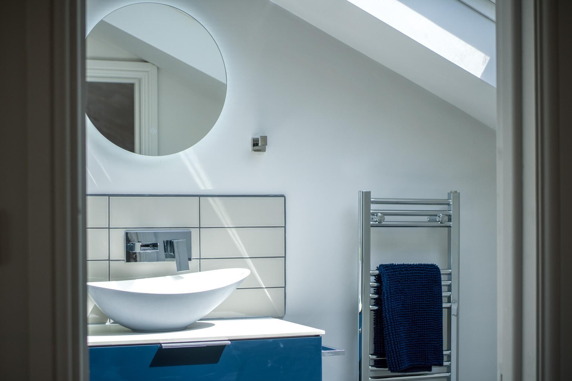 A modern bathroom with a skylight, a large oval sink, and a towel rack.