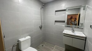 Une petite salle de bain moderne équipée de toilettes, d’une douche et d’un lavabo.