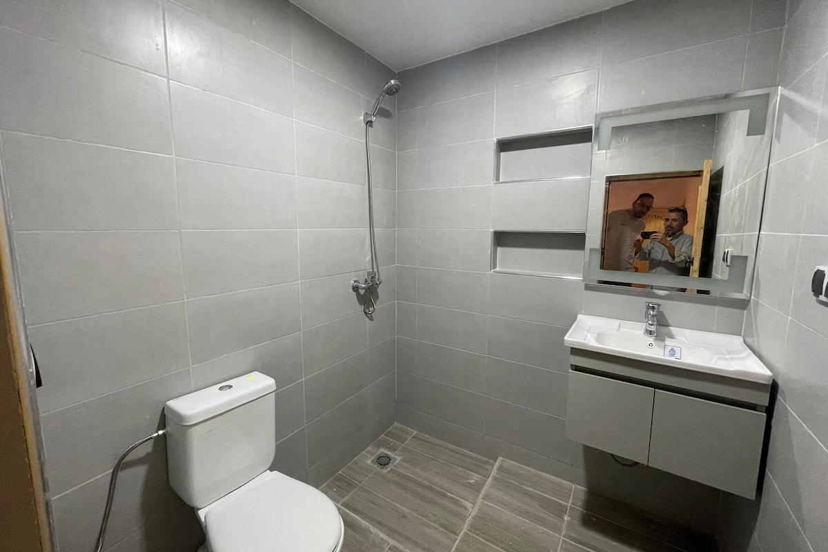 A small, modern bathroom with a toilet, shower, and sink.