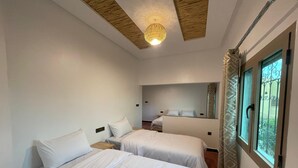 Une chambre d’hôtel avec deux lits, un grand miroir, un luminaire au plafond et une fenêtre donnant sur un beau paysage.