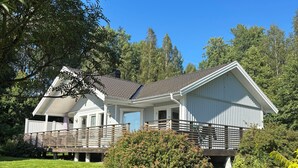 A two-story house with a covered porch, a fenced yard, and a well-maintained lawn. - Stylish Lakehouse retreat with views over Djulö (Katrineholm)