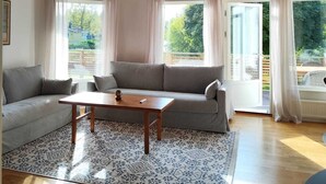 A spacious living room with a high ceiling, a grey sofa, a wooden coffee table, and a patterned rug. - Stylish Lakehouse retreat with views over Djulö (Katrineholm)