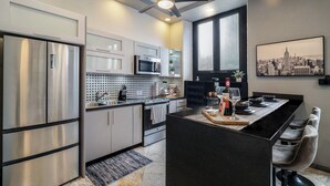 A modern kitchen with stainless steel appliances, a black island, and a cityscape view. - Designer Boutique 2-Bedroom Apartment in the Heart of Old San Juan (San Juan)