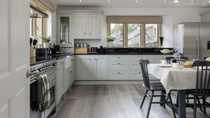 Una cocina moderna con armarios blancos, encimera negra y un comedor con mesa lista para dos.