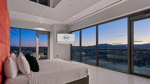Un dormitorio moderno con una cama grande, vistas a la ciudad y un cartel de StripViewSuites.com.