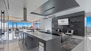 Una cocina moderna con una isla grande, un comedor con pared de mármol negro y vistas a la ciudad.
