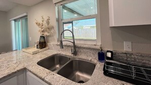 Una cocina con un lavamanos doble, una ventana con vistas y una encimera con un jarrón de flores.