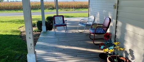 A covered porch with two chairs and a potted plant.