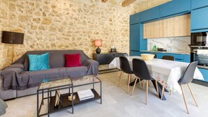 A cozy living room with a stone wall, a sofa with cushions, a coffee table, and a dining area with chairs and a table. - Authentic Charming Farmhouse With Pool in Gozo (Zebbug)