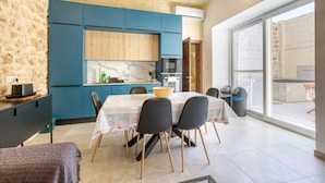 A modern kitchen with blue cabinets, a marble countertop, and a dining area with a table and chairs. - Authentic Charming Farmhouse With Pool in Gozo (Zebbug)