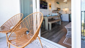 A modern kitchen with white cabinets, a wooden table, and wicker chairs. - Beachfront Luxe • Sleeps 6 • Best Location in CB! (Carolina beach)