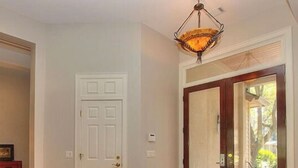 A hallway with a wooden floor, a patterned rug, a white door, and a large wooden door leading outside. - WALK TO BEACH! Pool/spa fenced yard. (Hilton Head Island)
