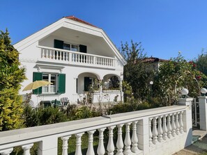 A two-story white building with a balcony, green shutters, and a garden. - Großmutters Ferienhaus by Interhome (Mörbisch am See)