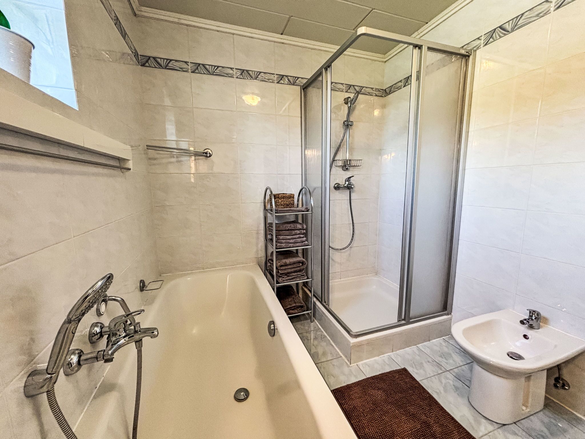A modern bathroom with a bathtub, shower, and bidet.