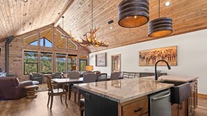 A spacious kitchen with a large island, wooden cabinetry, and a modern chandelier. - The Vue: Perfect Base for Zion & Bryce Adventures (Orderville)