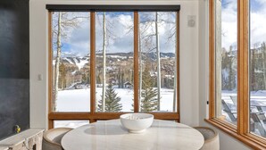 Ein Zimmer mit großem Fenster und Blick auf eine verschneite Landschaft und Berge.
