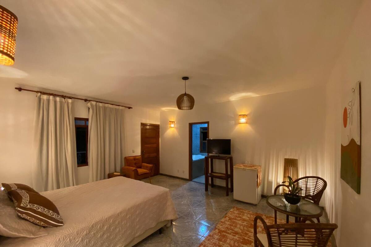 Une chambre d’hôtel équipée d’un lit, d’un bureau, d’une chaise, d’une télévision et d’un petit réfrigérateur.