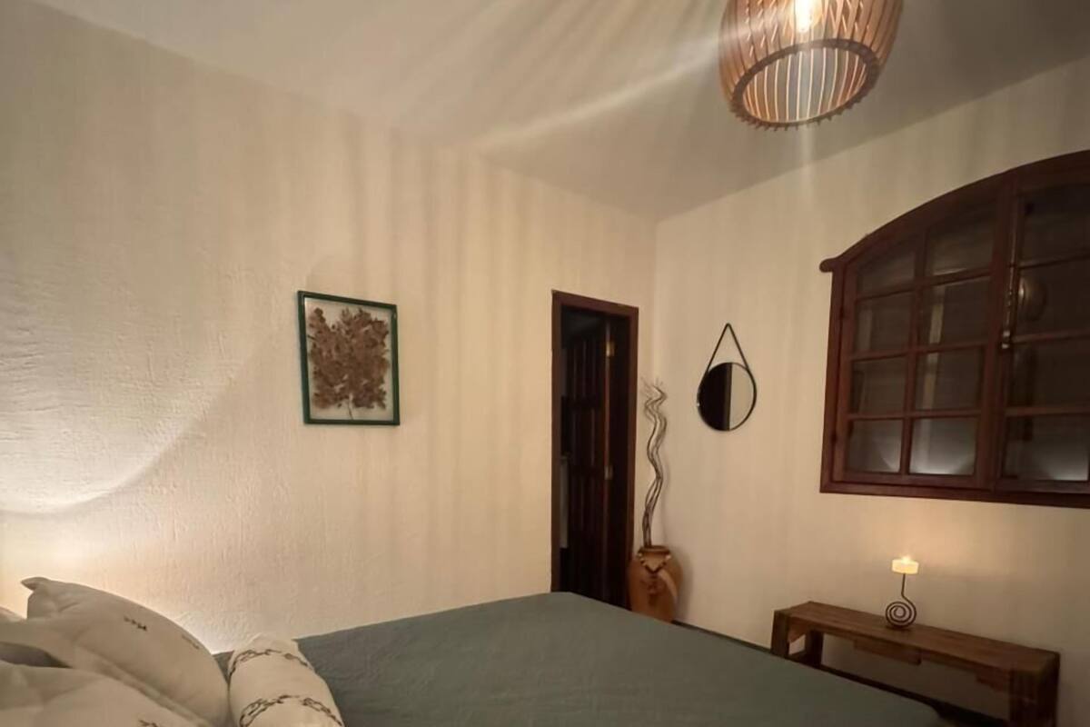 Une chambre à coucher avec un grand lit, une table de chevet avec une lampe, une armoire en bois et un tableau encadré au mur.