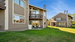 A two-story house with a balcony, a covered patio, and a well-maintained lawn. - Charming 2-bedroom condo short walk to main lift (Somerset)