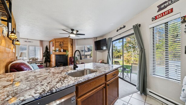 A modern kitchen with a granite countertop, wooden cabinets, and a built-in dishwasher. - Charming 2-bedroom condo short walk to main lift (Somerset)