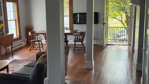 Un vaste espace de vie doté d’un plancher en bois, d’un canapé, d’une table à manger avec des chaises et d’un téléviseur fixé au mur.