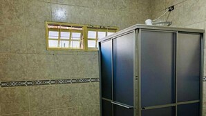A bathroom with a tiled floor, a shower enclosure, a window, and a towel mat.