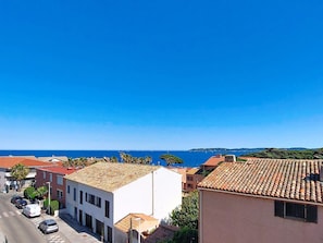 A coastal town with buildings, a clear blue sky, and the sea in the background.
