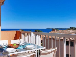 A balcony with a table set for two, overlooking a coastal view.