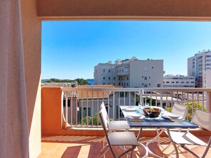 Ein Balkon mit Esstisch, weiĂen StĂŒhlen und Blick auf die umliegenden GebĂ€ude.