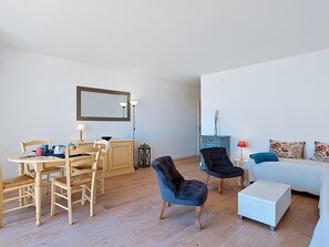 Ein Wohnzimmer mit Esstisch, StĂŒhlen, einer Couch, einem Couchtisch und einer Lampe.