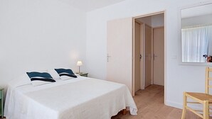 A bedroom with a bed, a nightstand, a lamp, a chair, and a mirror. - La Marjolaine by Interhome (Sainte Maxime)