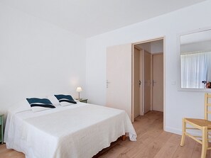 Une chambre à coucher comprenant un lit, une chaise, une lampe et une porte donnant sur une autre pièce.