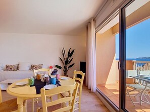 A dining area with a round table, chairs, and a sofa in the background.